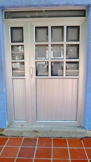 Puerta doble de aluminio con diseño de cuadros - Vidrería El Cristal